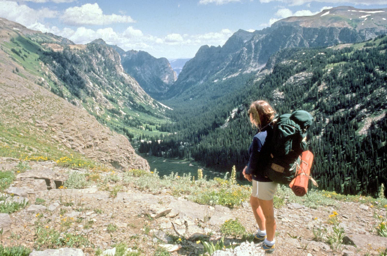 A trekker carrying a fully loaded backpack into the mountains